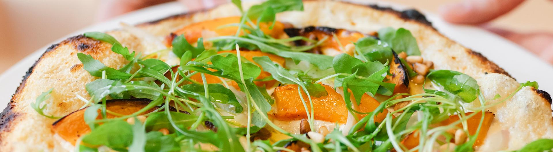 Pizza blanche, Crème Fraîche, courge rôtie, oignons confits, pousses de roquette et pignons de pin