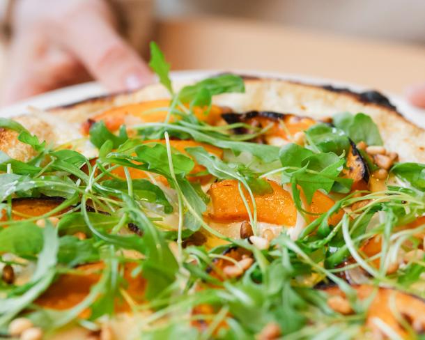 Pizza blanche, Crème Fraîche, courge rôtie, oignons confits, pousses de roquette et pignons de pin